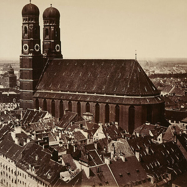 Historische schwarzweiß-Fotografie einer großen Kirche mit zwei Türmen innerhalb eines Stadtgebiets.