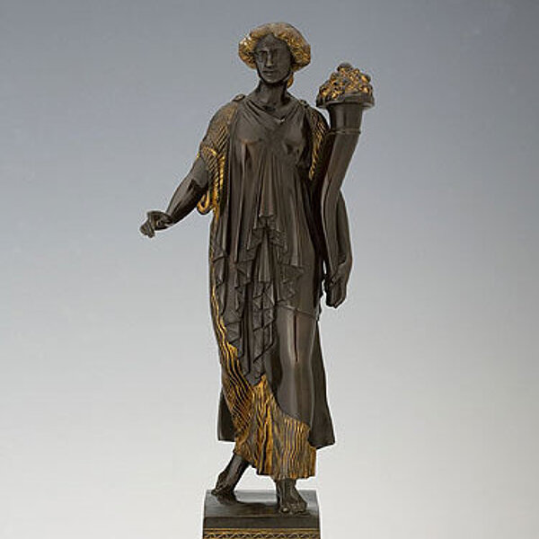 Skulptur einer Frau mit Füllhorn, goldene Verzierungen auf einem Sockel.