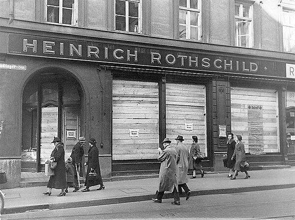 Historische Schwarz-weiß-Fotografie, Außenansicht des Geschäfts „Heinrich Rothschild“, die Fenster mit Holz vernagelt.