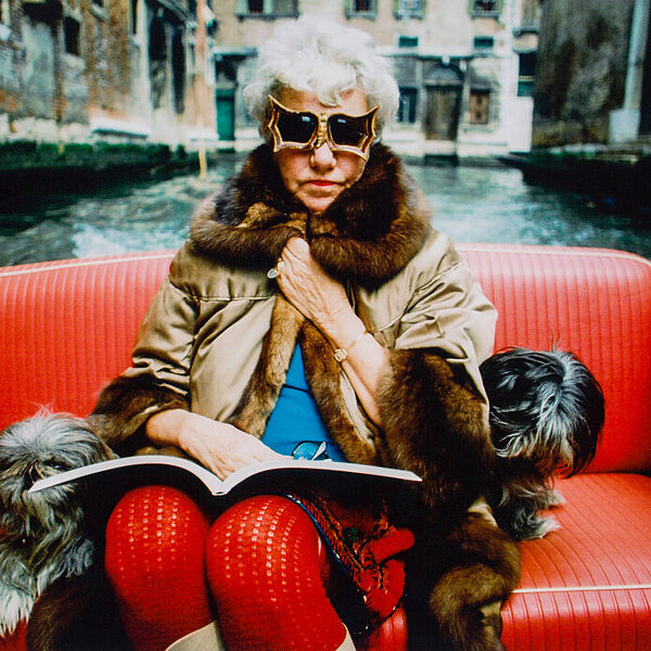 Dame mit Hund und Sonnenbrille sitzt auf rotem Ledersessel in einem Boot
