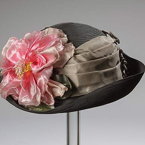 Dunkler Hut mit glänzend rosa Stoffblume.