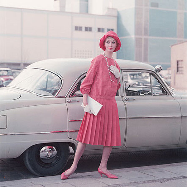 Farbige Modefotografie der 50er Jahre, schicke Frau vor einem Auto.