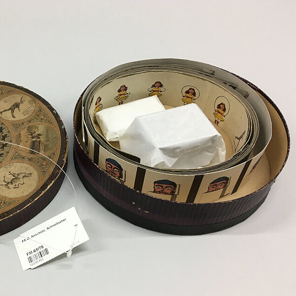 Geöffnete runde Box aus Karton mit Rolle von Bildern und Deckel